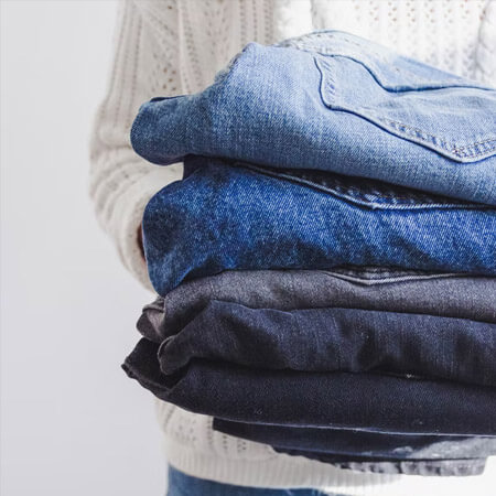 woman holding pile of jeans